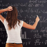 Mladá žena sa pozerá na matematický problém na tabuli